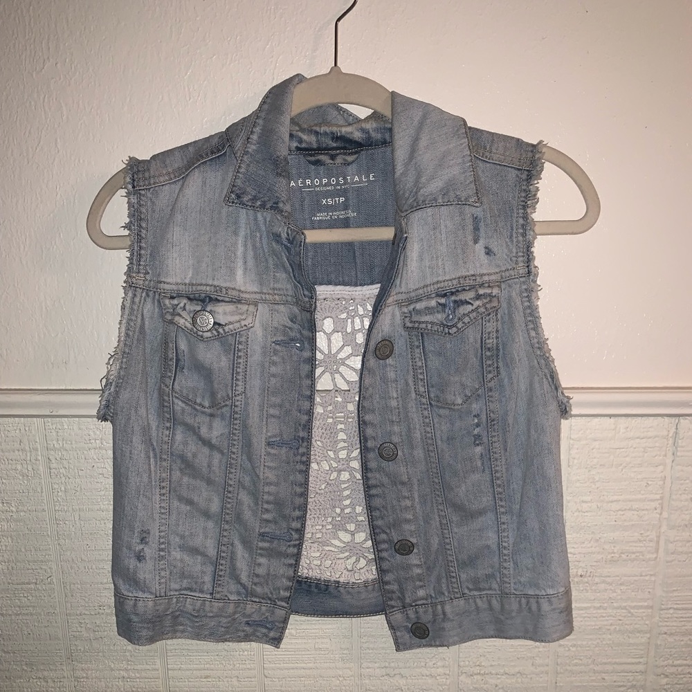 Used sleeveless blue jean jacket with distress detail